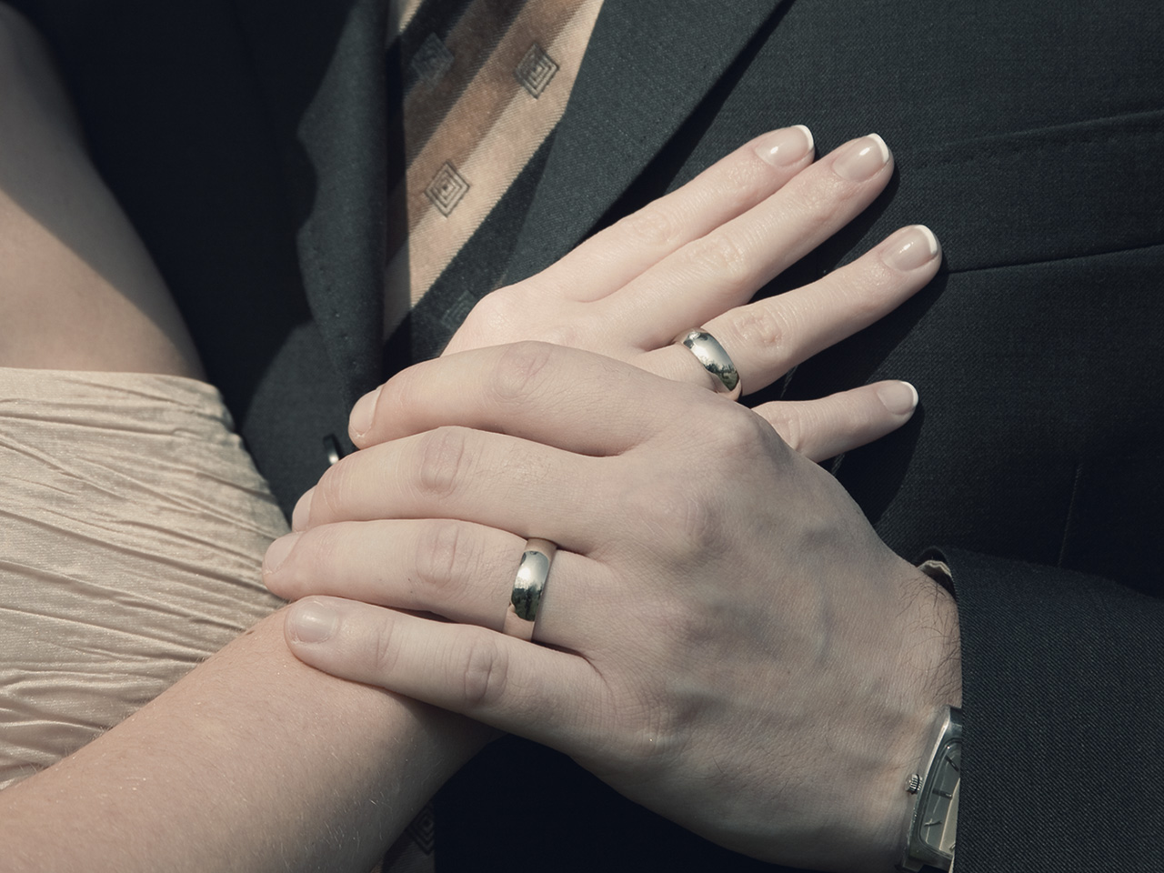 Мужская рука держит женскую руку с обручальными кольцами